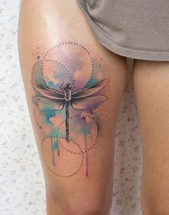 Tatuaggi di libellula sulla coscia con motivi circolari di sfondo e acquerello gocciolato