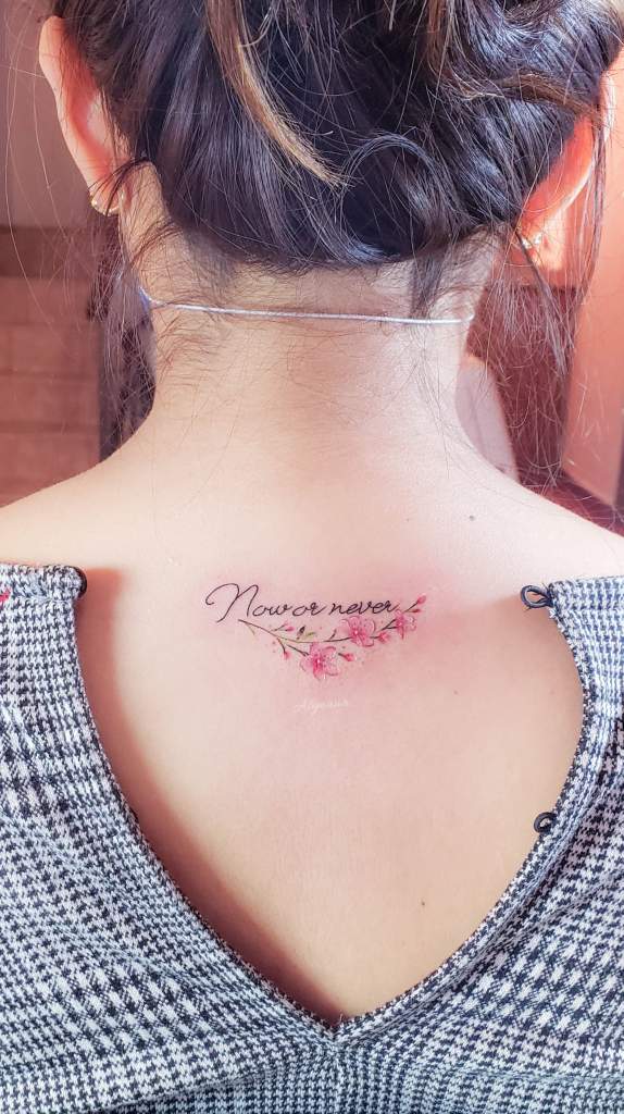 16 Estudio Alynana Tattoo CDMX Inschrift „Now or Never Now or Never“ mit einem Strauß rosa Blumen auf dem Rücken unterhalb des Halses