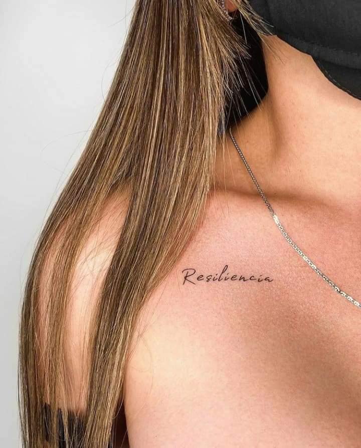 21 Word Resilience Wings Tattoo mit feinen Buchstaben auf dem Schlüsselbein
