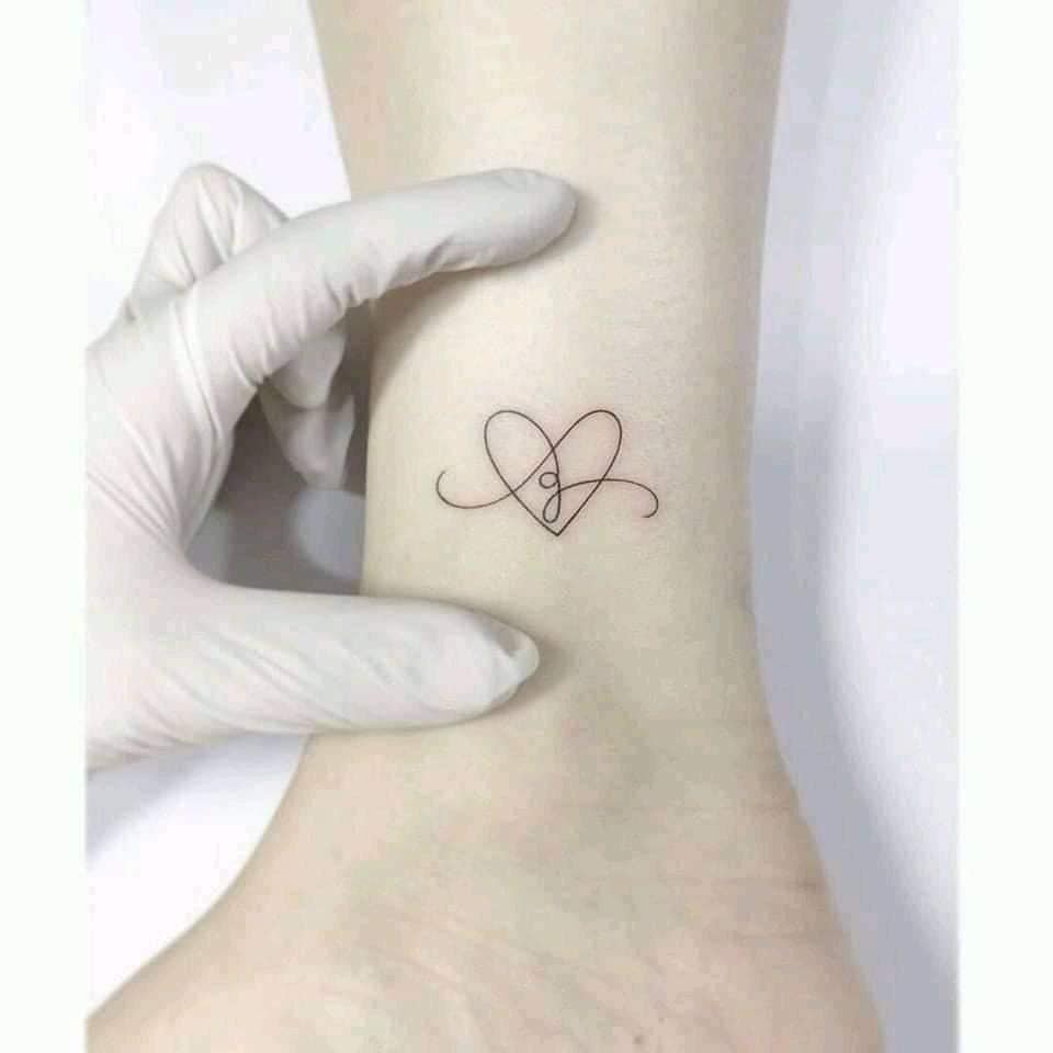 33 Tatuagens de Letras e Iniciais Letra minúscula g com linha fina de coração no tornozelo