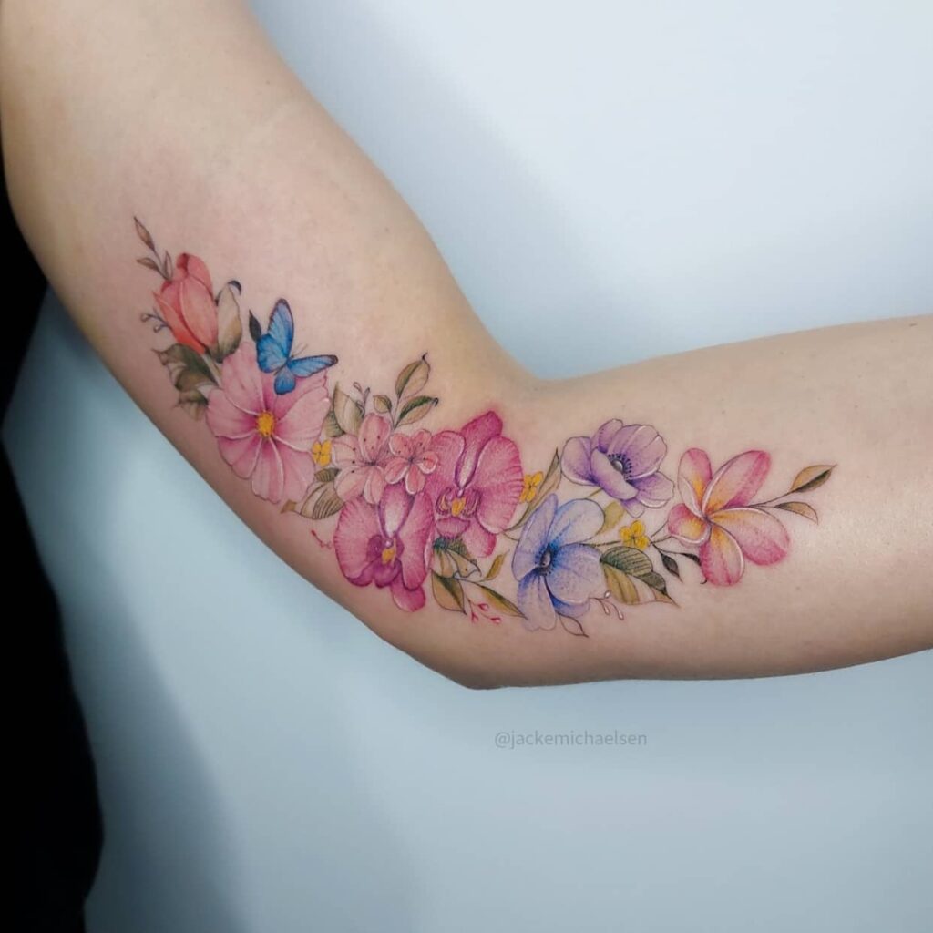 9 Künstler Jacke Michaelsen BR Tattoos Blumenstrauß auf Arm und Unterarm mit blauen Schmetterlingsblütenblättern Setzlinge Zweige