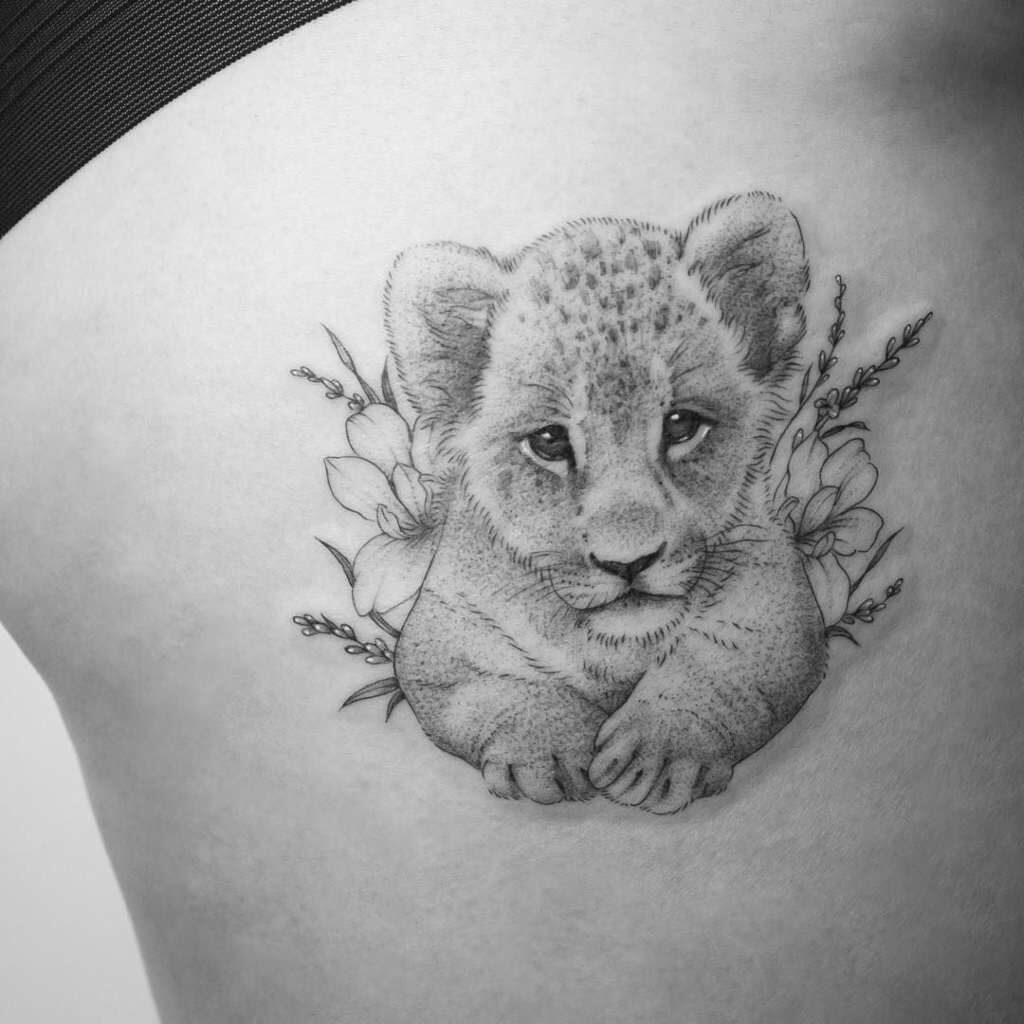 Tatuaggio della Leonessa e dei suoi cuccioli Immagine di un singolo cucciolo di leone, un figlio con fiori dietro e un viso tenero