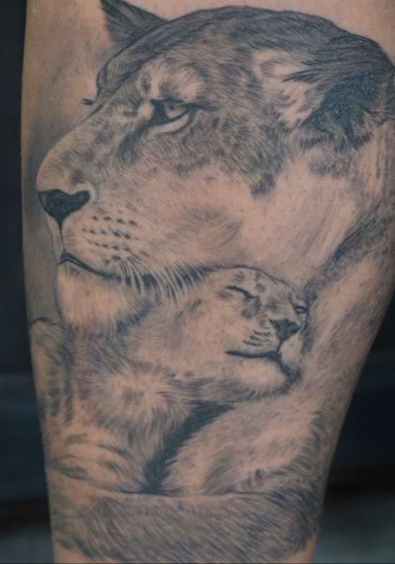 Tätowierung einer Löwin und ihrer Jungen. Löwin umarmt und beschützt einen Sohn und ein Junges mit zufriedenem Gesicht