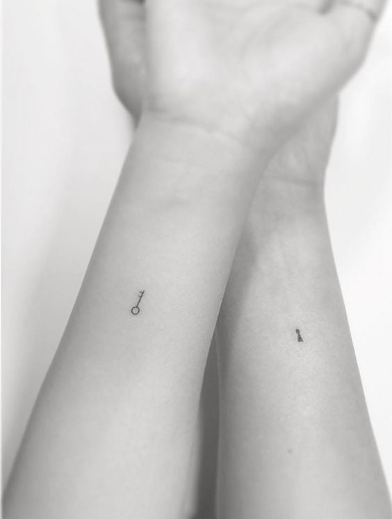 Semplici tatuaggi carini ed estetici su entrambi gli avambracci, uno un piccolo lucchetto, l'altro una piccola chiave