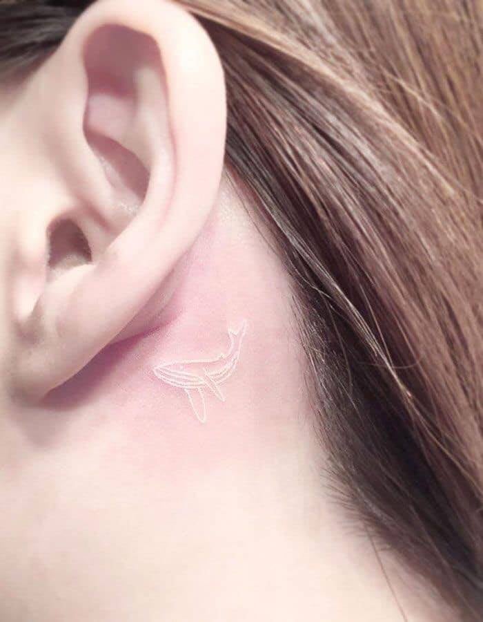 Tattoos mit weißer Tinte. Diskreter und minimalistischer Wal hinter dem Ohr