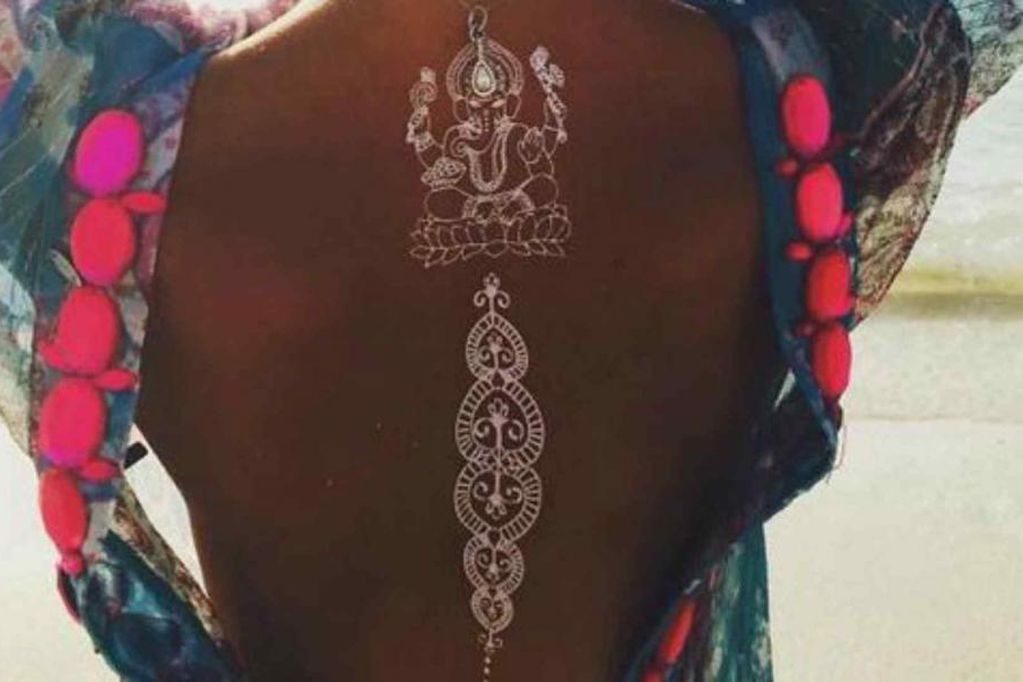 Tatuaggi con inchiostro bianco su pelle marrone Dio Indu e mandala sul retro