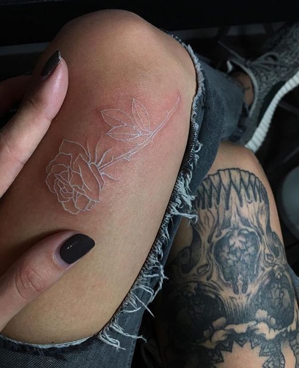 Tatuaggi con inchiostro bianco su pelle marrone Piccola rosa sulla gamba