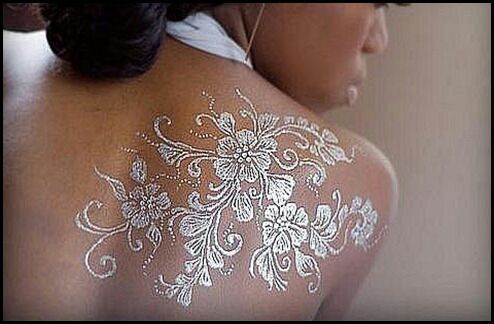 Tattoos with white ink on brown skin flower arrangement on shoulder blade