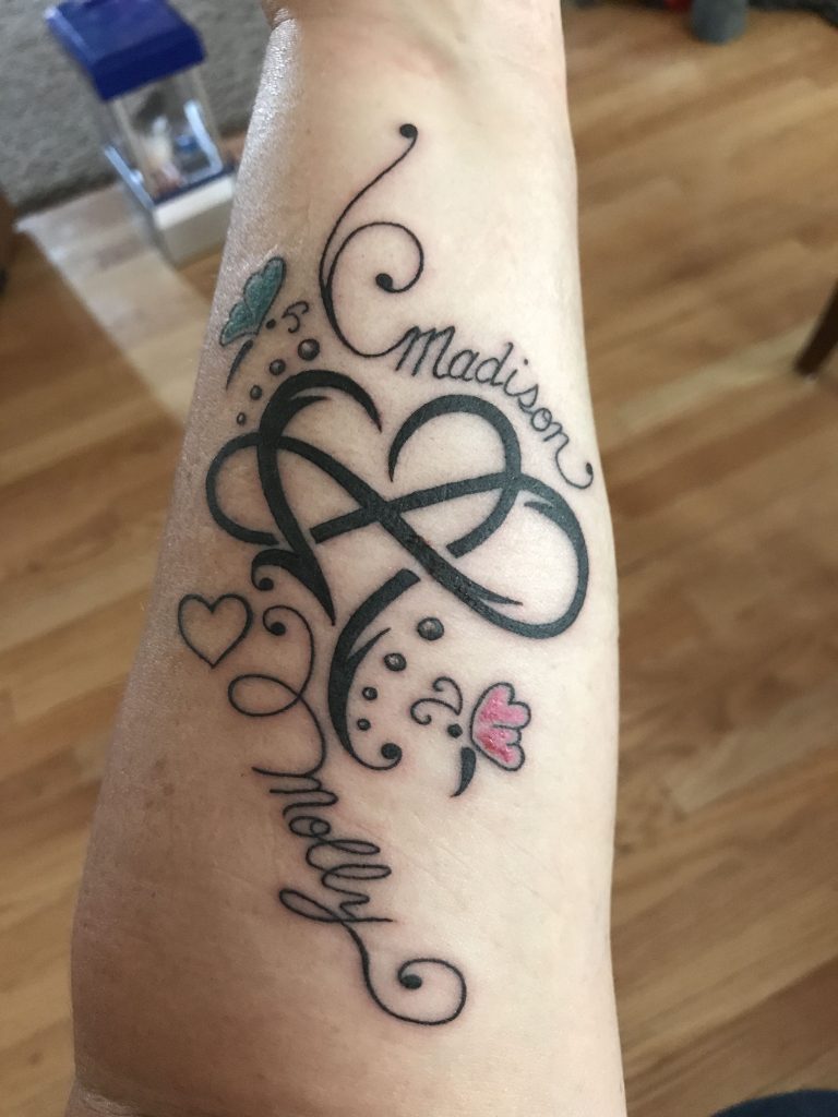 Tattoos der unendlichen Liebe, verflochten mit einem herzförmigen schwarzen Band mit Schmetterlingen namens Molly Madison, Herz auf dem Unterarm