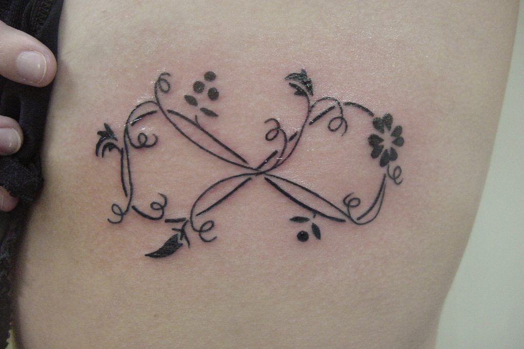 Tatuajes de Amor Infinito con ramitas flores adornos en negro trebol