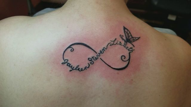 Tatuaggi Infinite Love sulla schiena sotto il collo con tre nomi e una farfalla Jayleen Steven Lisbeth
