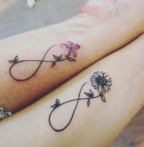 Tatuagens Amor Infinito nos pulsos de mãe e filha com uma flor rosa em um e um girassol preto com folhas no outro