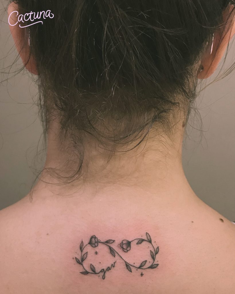 Infinite Love-Tattoos aus Zweigen und kleinen Blumen trugen die Inschrift unter dem Nacken und am Rücken