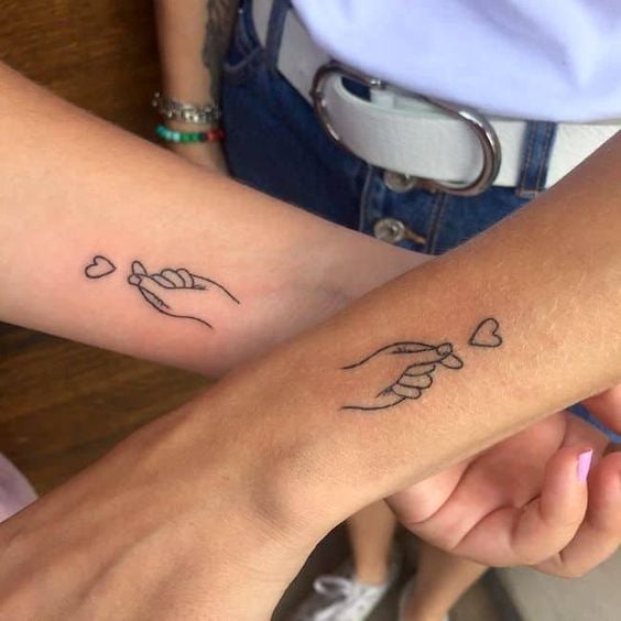 Tatouages de coeurs pour couples sœurs amis sur les poignets main avec les doigts ensemble et le cœur se lève