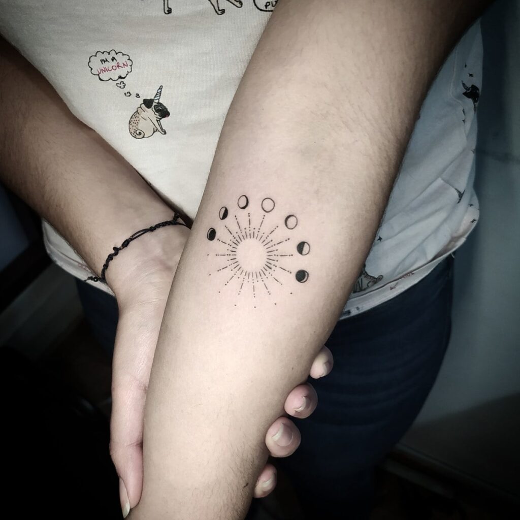 Tattoos of concentric Moon Phases and in the half sun on the forearm in black