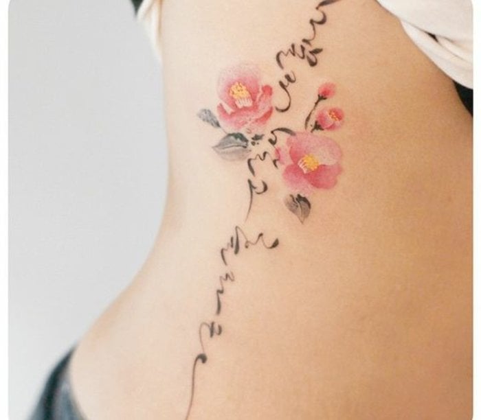 Tatuaggi floreali sulle costole Fiori rosa con boccioli e stelo con tratto artistico