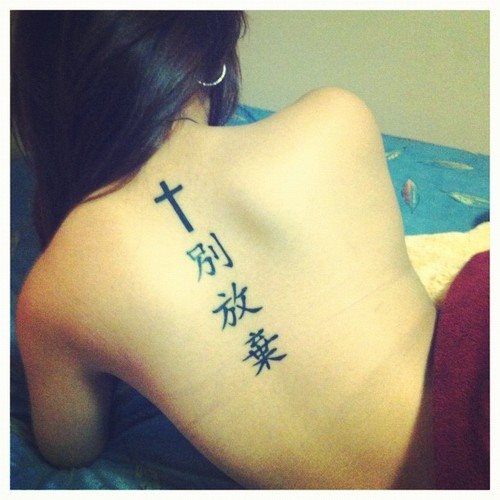 Tatuagens de símbolos de letras chinesas japonesas e cruz de significado nas costas seguidas ao longo da coluna com três caracteres