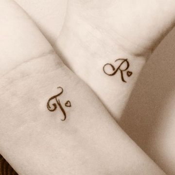 Tatuajes de Letras e Iniciales para parejas letras T y R con pequenos corazoncitos en muneca