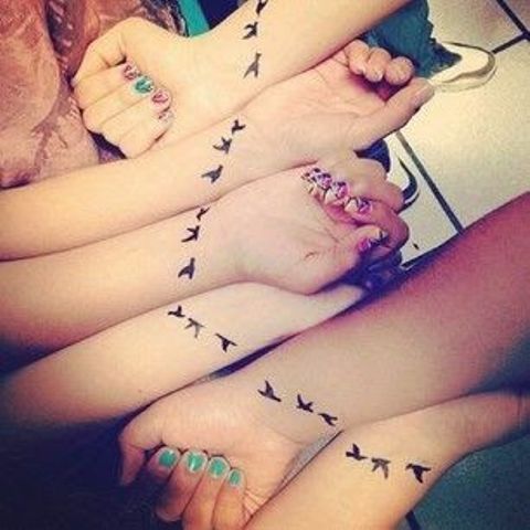 Tatuaggi per sei amici, sorelle, cugini. Uccelli in volo sui polsi che insieme possono essere visti come uno stormo