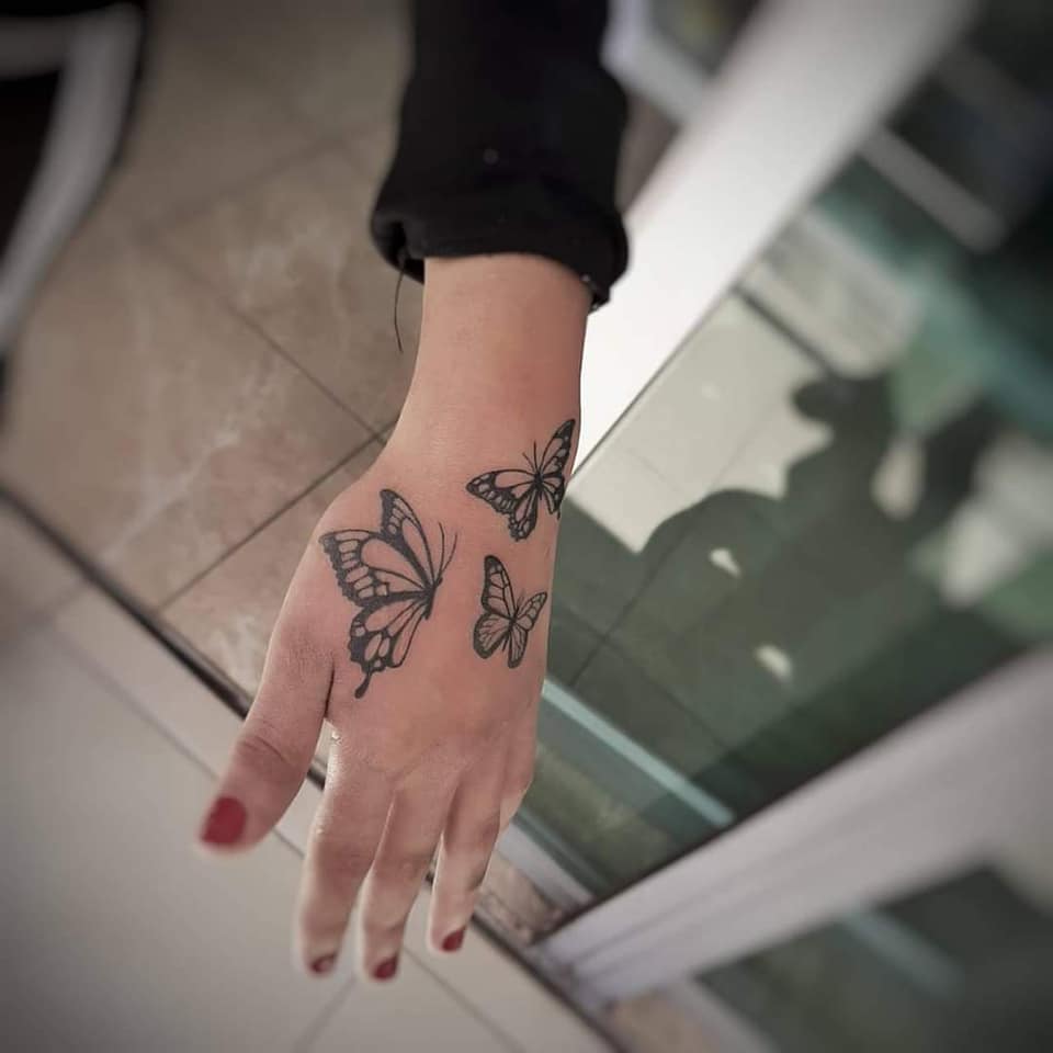 Tattoos für Frauen sind die beliebtesten Drei schwarze Schmetterlinge auf der Hand