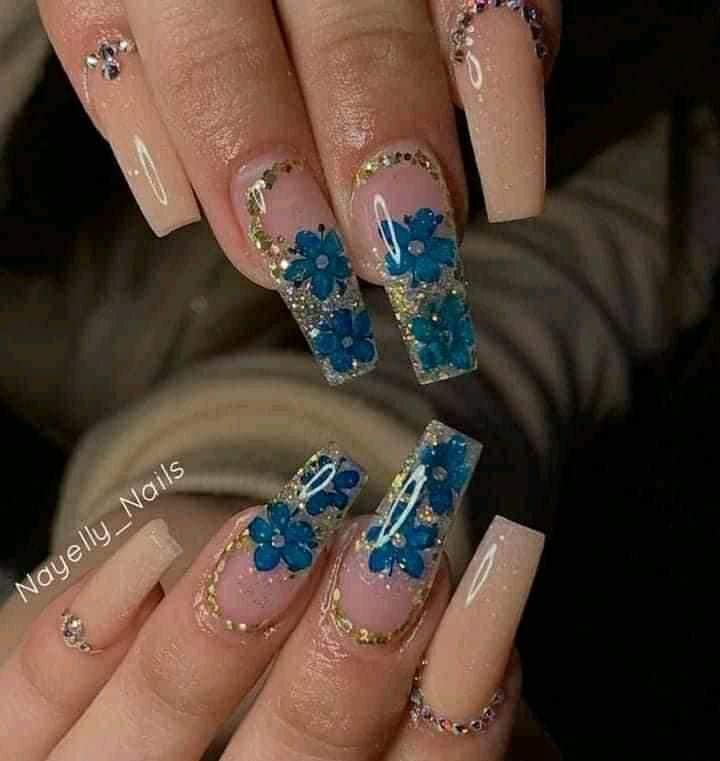 Natürliche und transparente, verzierte Nägel mit Einlagen aus blauen Blumen, die der Natur ähneln