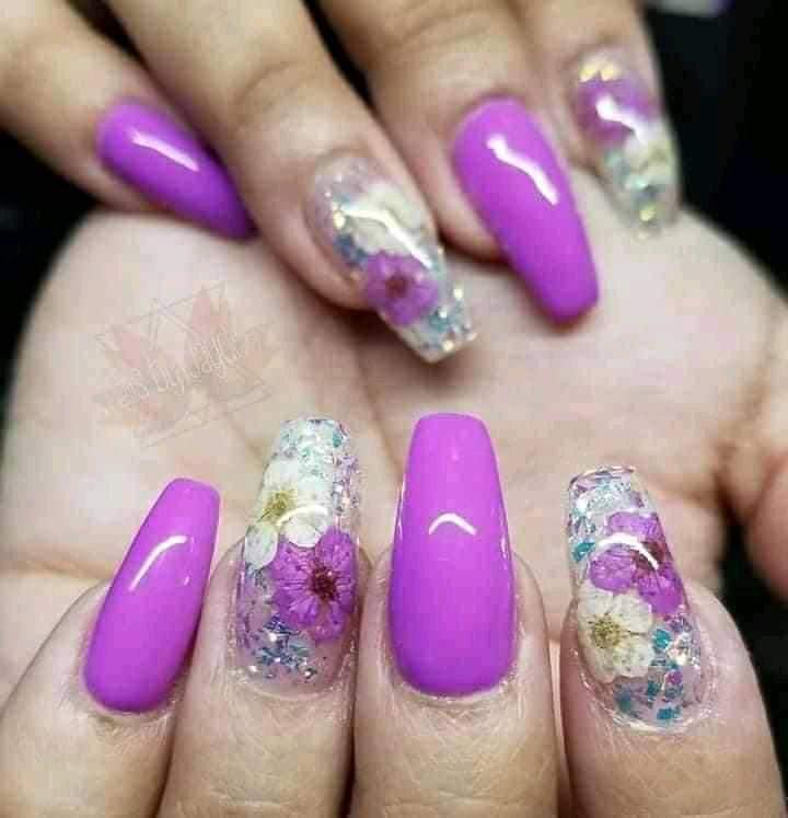 Verzierte violette und transparente Nägel mit eingelegten violetten und weißen Blumen, die der Natur ähneln