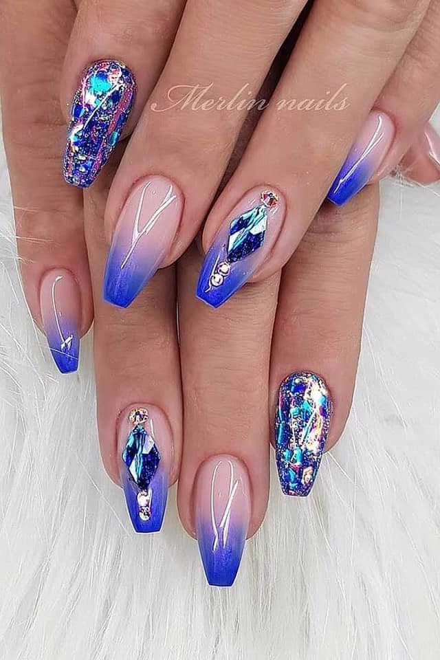 Some Blue Acrylic Nails with diamond-shaped gems and mother-of-pearl decorations