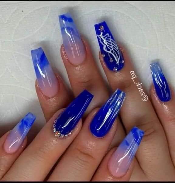Des ongles en acrylique bleus et roses avec des détails d'ailes d'ange blanches