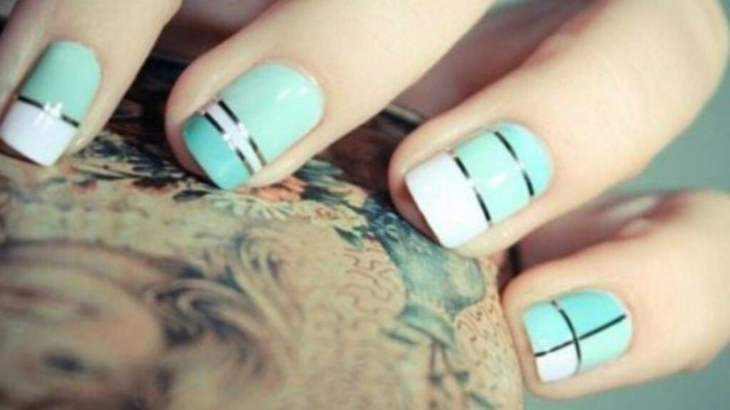 Quelques ongles en acrylique en blanc et bleu clair avec des lignes argentées