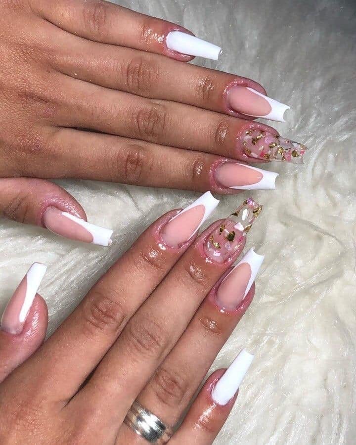 Des ongles en acrylique rose avec du blanc sur les pointes et transparents avec des décorations argentées à l'intérieur
