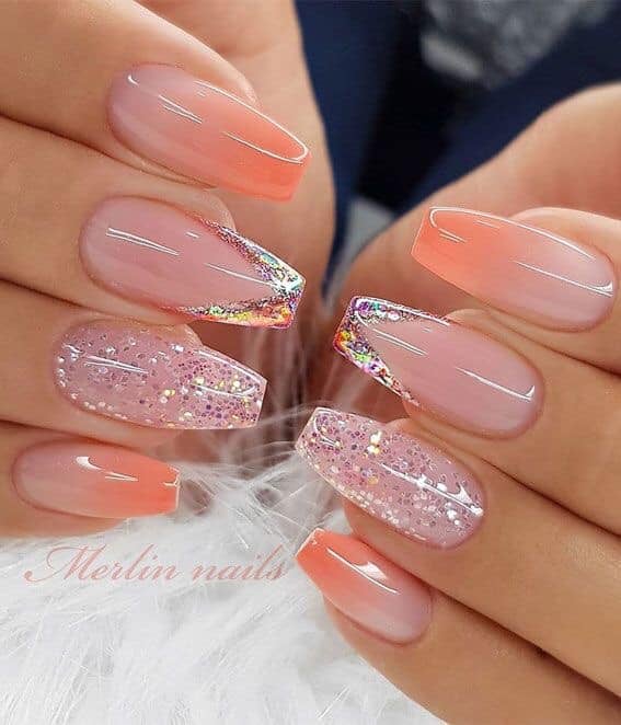 Des ongles en acrylique rose et saumon brillants avec un intérieur avec des paillettes