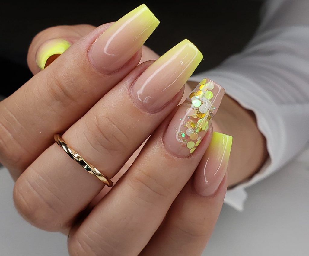 Quelques ongles en acrylique naturel et jaune incrustés de pétales jaunes