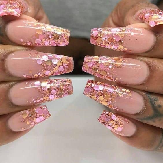 Alcune unghie acriliche in tutto rosa e oro con esagoni lucidi all'interno