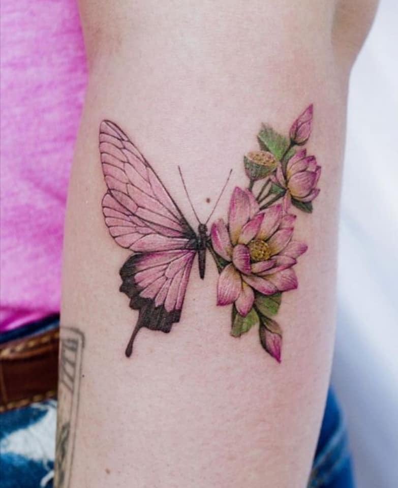 15 Schmetterlings-Tattoos kombiniert mit rosa Blumen und grünen Blättern auf dem Unterarm