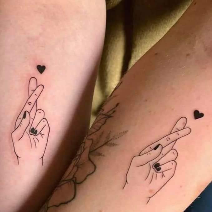 15 tatuagens para melhores amigos nos dedos indicador e médio cruzados com um coração no braço