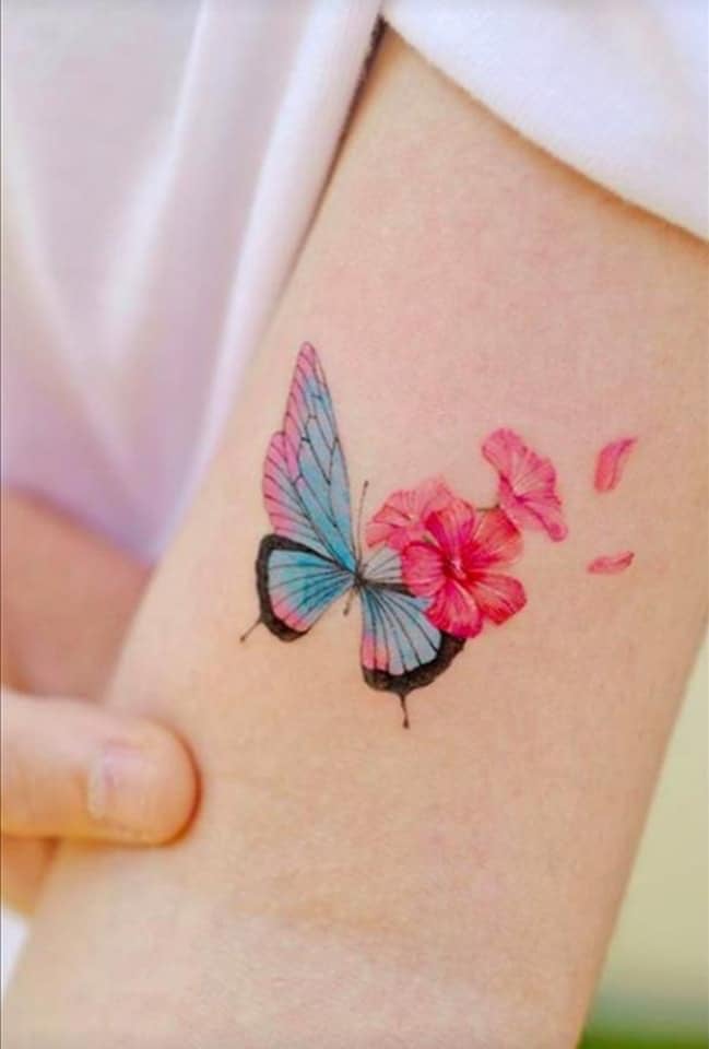 17 Tattoos eines rosa Himmelsschmetterlings mit kleinen roten rosa Blumen auf dem kleinen minimalistischen Arm