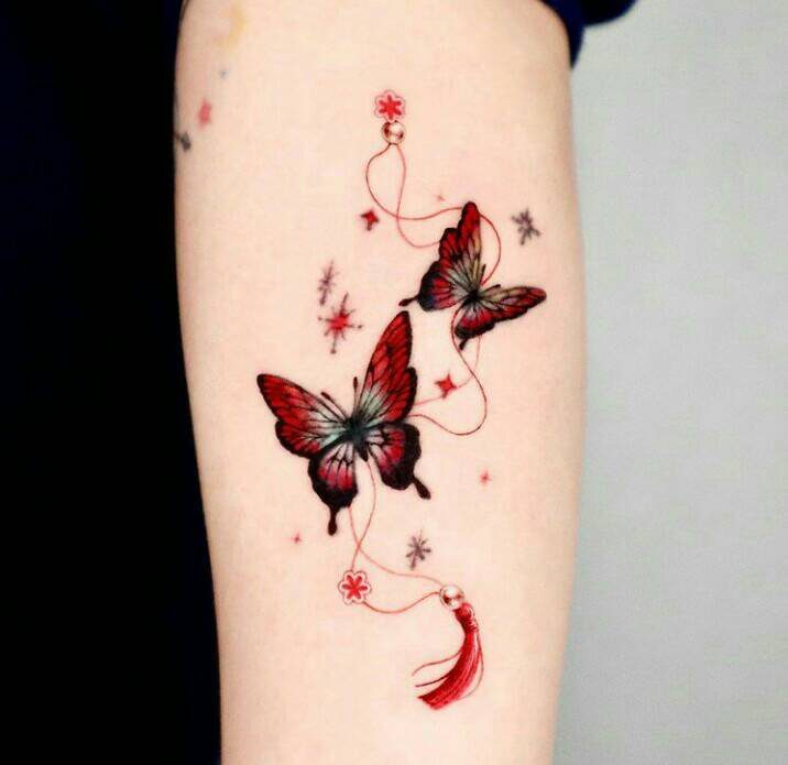 190 Tatuagens de borboletas vermelhas e pretas intensas com penas indígenas e fio vermelho com estrelas no braço