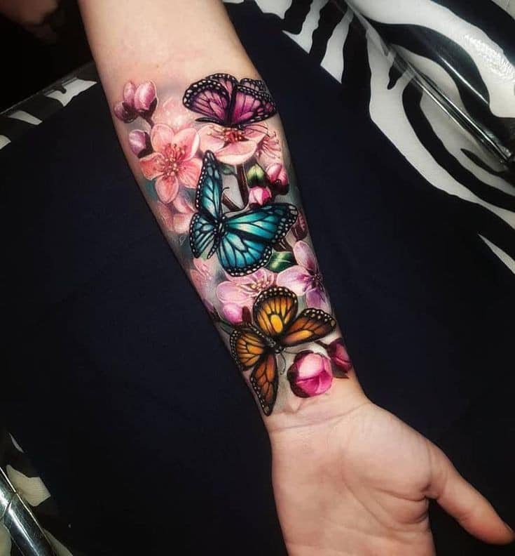 223 Realistico tatuaggio colorato di fiori gialli e farfalle rosa azzurro sull'avambraccio