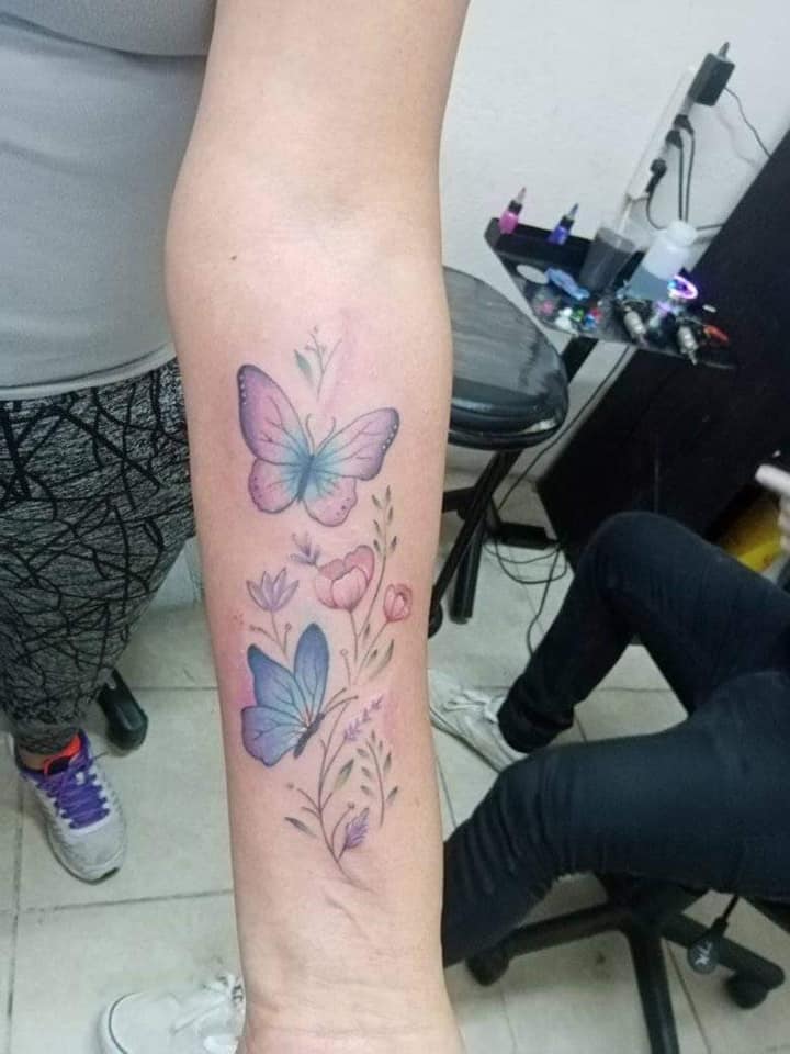 34 Tatuaggi più apprezzati per le donne Fiori viola e rosa con foglie e ramoscelli sull'avambraccio