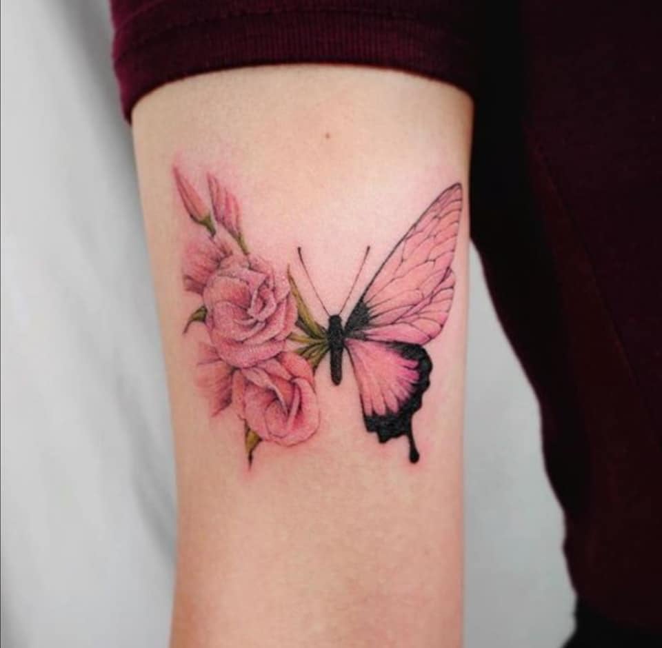 6 tatuaggi a farfalla combinati con fiori rosa sul braccio