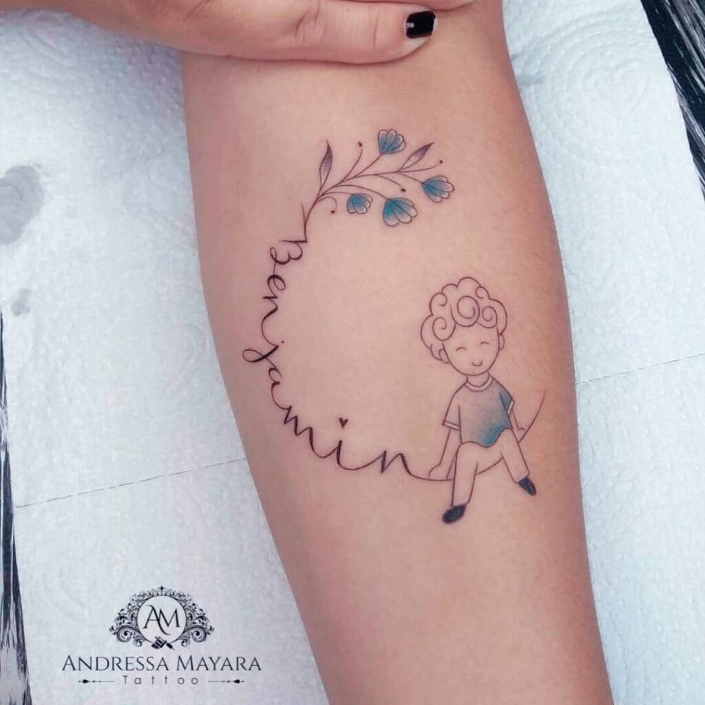Tattoo eines auf einem Zweig sitzenden Kindes mit hellblauen Blumen und dem Namen Benjamin der Künstlerin Andressa Mayara Santa Catarina Brasilien