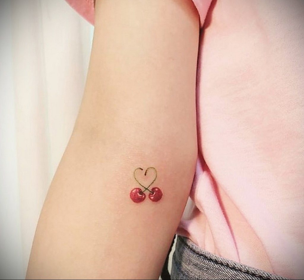 Kleine Kirschen und Herz-Tattoos auf dem Unterarm