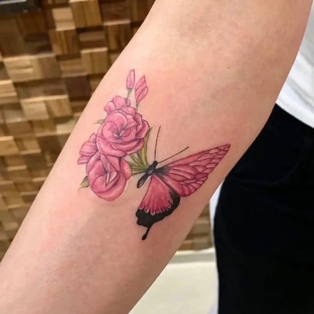 Tattoos von wunderschönen rosa Schmetterlingen mit halben Flügeln und halben Blumen mit Knospen und Zweigen auf dem Unterarm