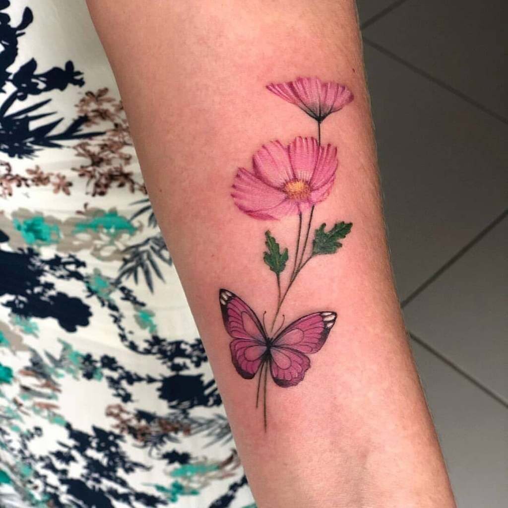 Tatuajes de Mariposas Bellos Rosa en antebrazo pequena y delicada con ramitas hojas verdes y flores cosmos rosados