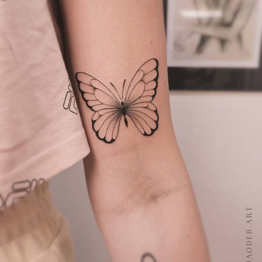 Tatuajes de Mariposas Bellos alas definidas con contorno negro en brazo