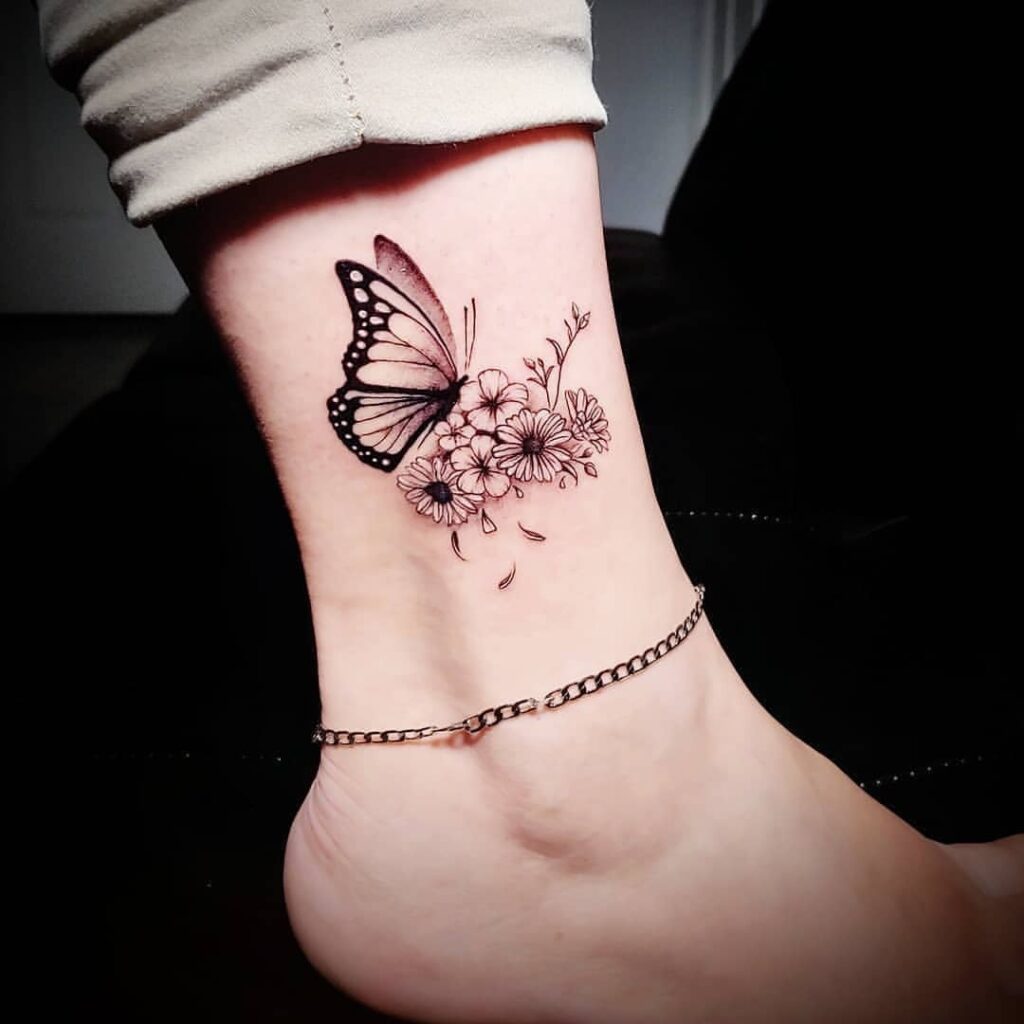 Wunderschöne Schmetterlings-Tattoos auf schwarzem Knöchel, die auf Blumen und Zweigen sitzen