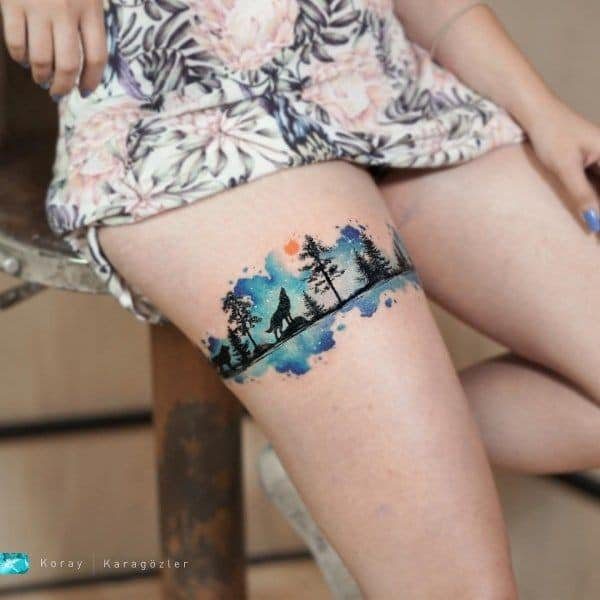 106 tatouages sur la cuisse une garde de type aquarelle avec paysage de forêt de loups pins ciel céleste non