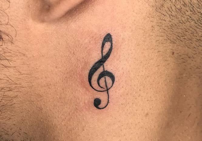 Die 3 TOP 3 kleinen Tattoos für Männer: Notenschlüssel im Violinschlüssel unter dem Ohr