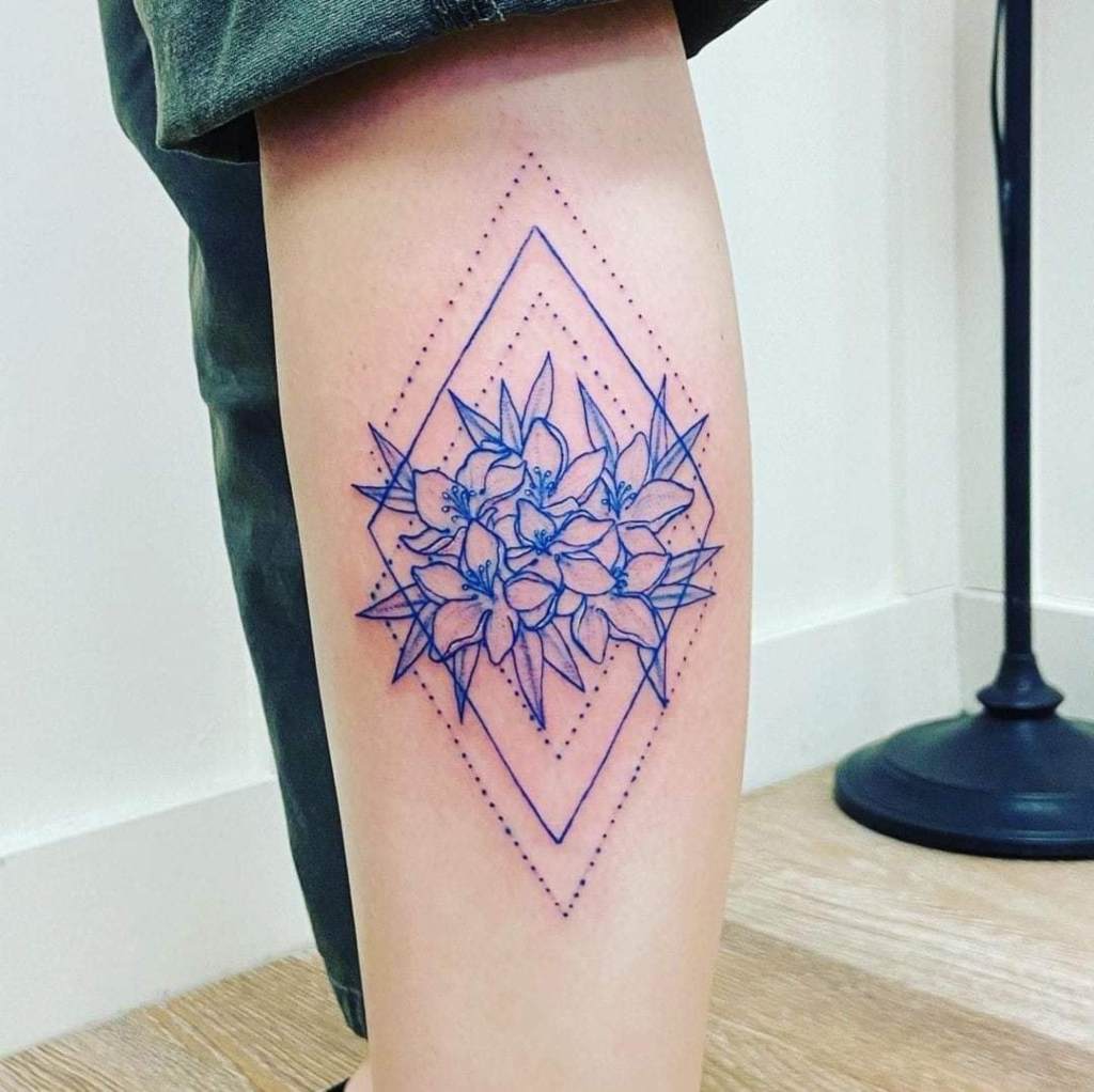 8 tatuagens Blue Contour de flores inscritas em losangos geométricos com uma linha pontilhada no braço