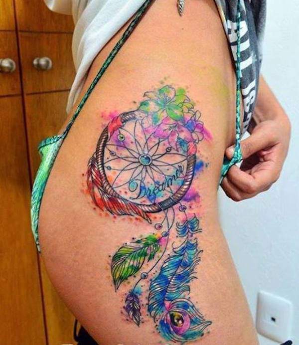 Tatuagem na coxa de uma mulher Angel Caller em cores com inscrição Dreamer e penas